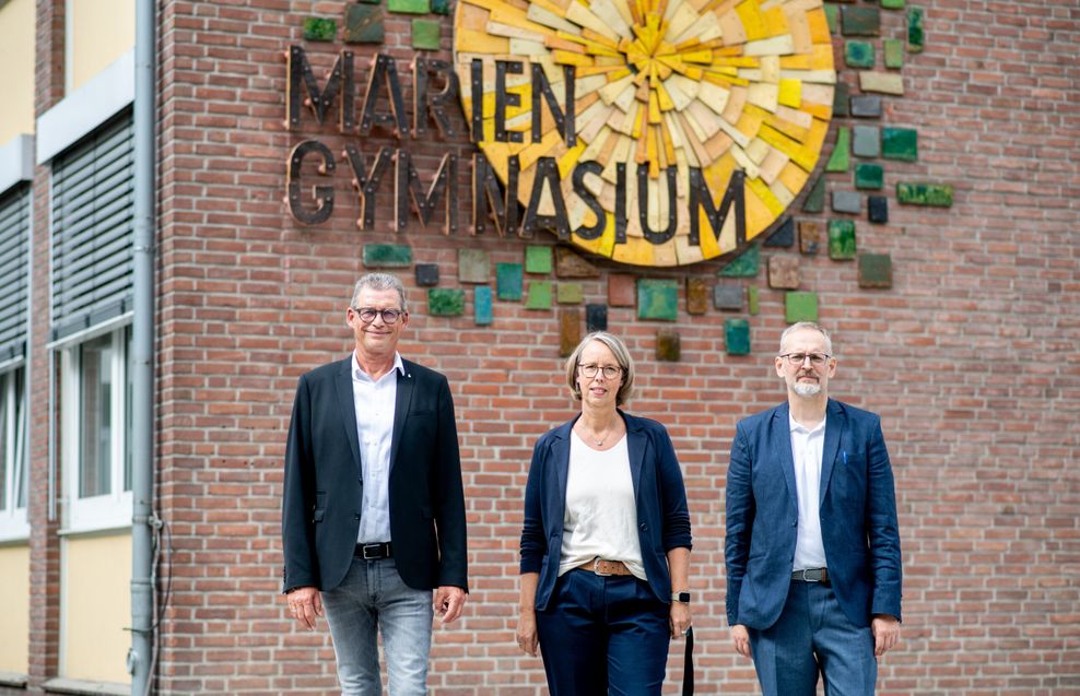 Schulleiter Michael Blömer (l.), sein Stellvertreter Arne Fuchs (r.) und Lehrerin Britta Kassens-Hesener vor dem Schulgebäude.