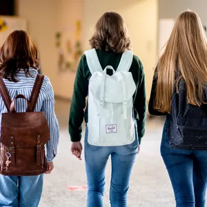 Drei Mädchen mit Rucksäcken auf den Rücken gehen durch eine Schule