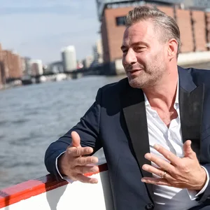 Sasha sitzt auf einem Boot, das vor der Elphi schippert, und spricht