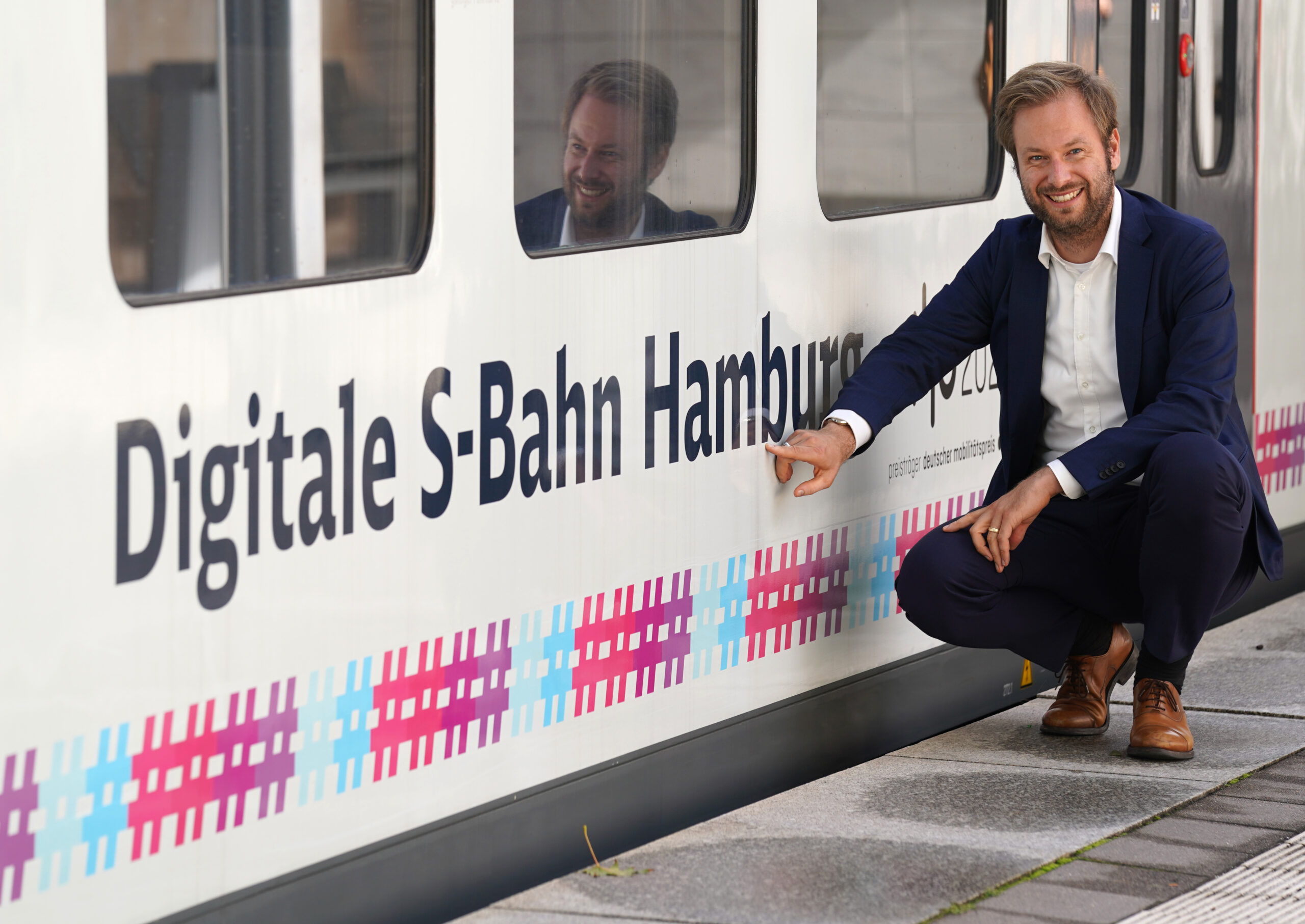 Anjes Tjarks (Bündnis 90/Die Grünen), Senator für Verkehr und Mobilitätswende, zeigt auf den Schriftzug „Digitale S-Bahn Hamburg“ an einer S-Bahn der Linie S2 am Bahnhof Bergedorf.