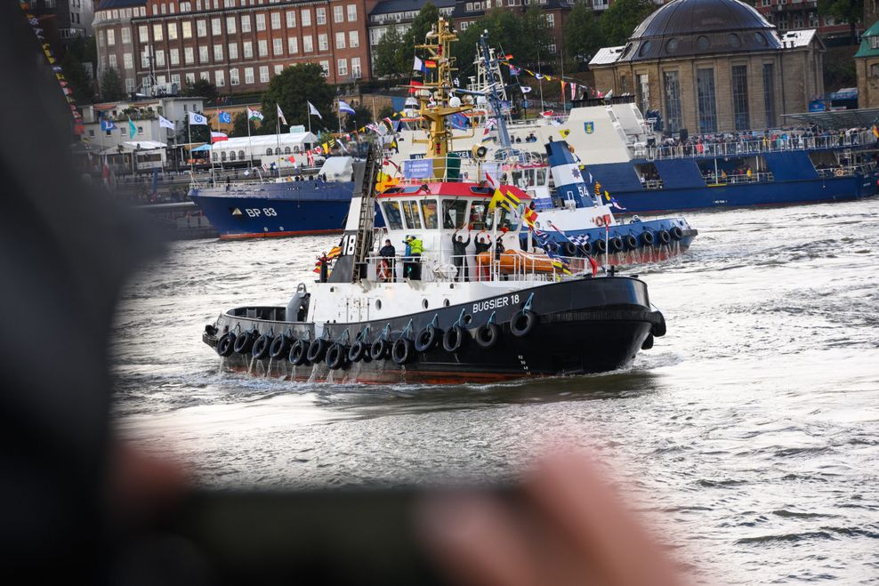 Schaulustige beobachten mehrere Schlepper beim traditionellen Schlepperballett auf der Elbe vor den Landungsbrücken.