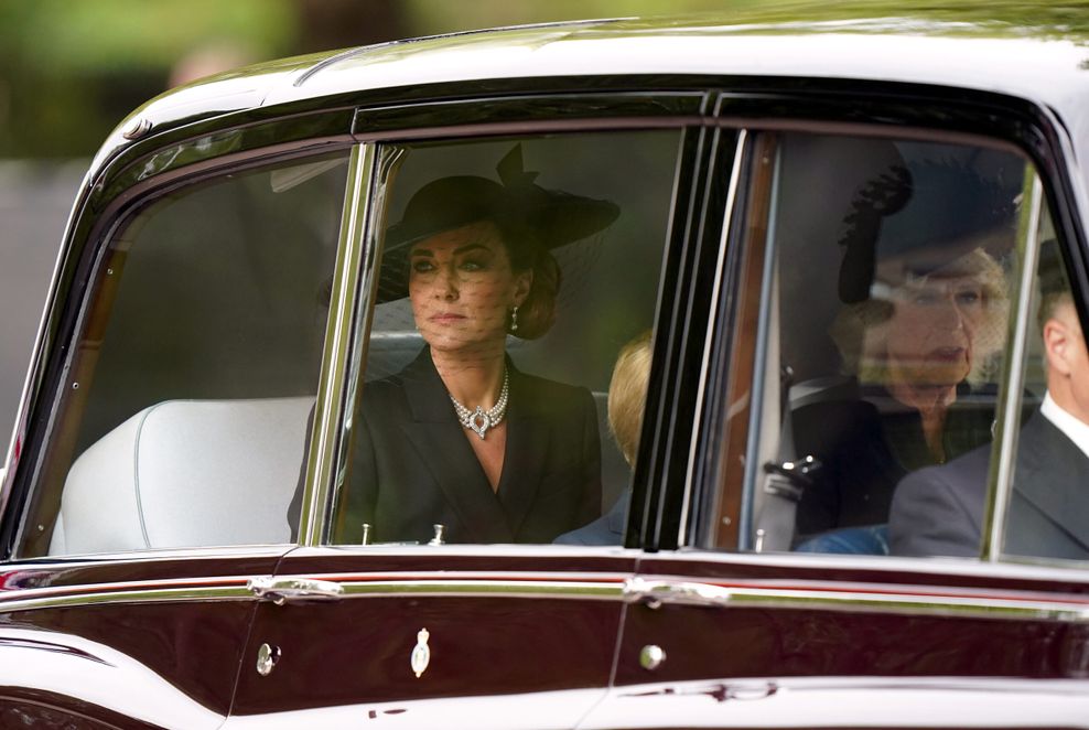 Kate sitzt auf dem Rücksitz eines Autos