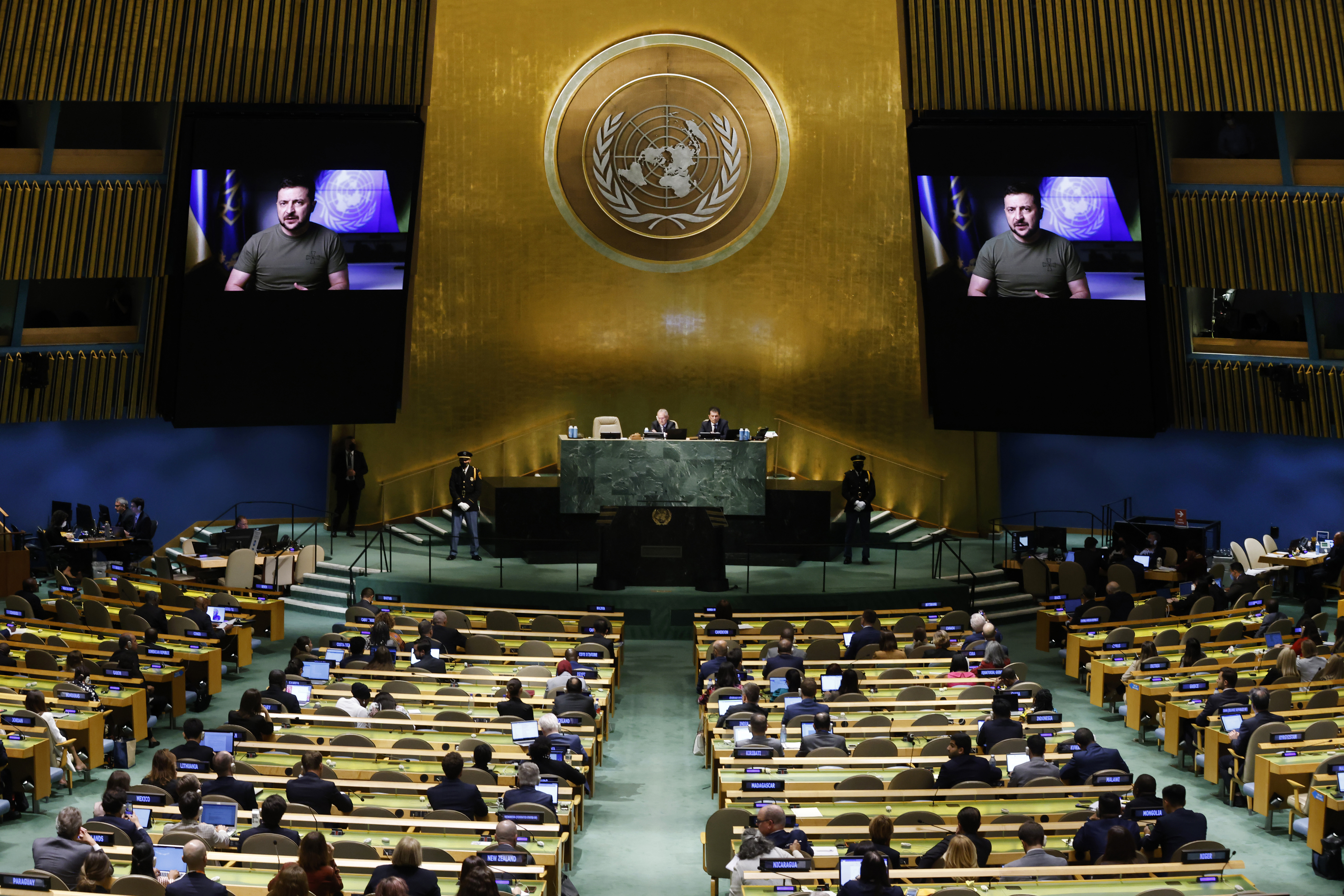 Selenskyj ist auf einem Bildschirm zu sehen, im Plenum sitzen Mitglieder der Generalversammlung