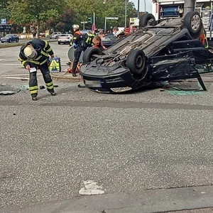 Zwei zerstörte Autos sind auf der Straße zu sehen, eines liegt auf dem Dach, vor Ort viele Rettungskräfte