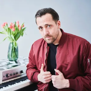 Rechts sitzt Danger Dan, links, auf dem E-Klavier, ein Hund