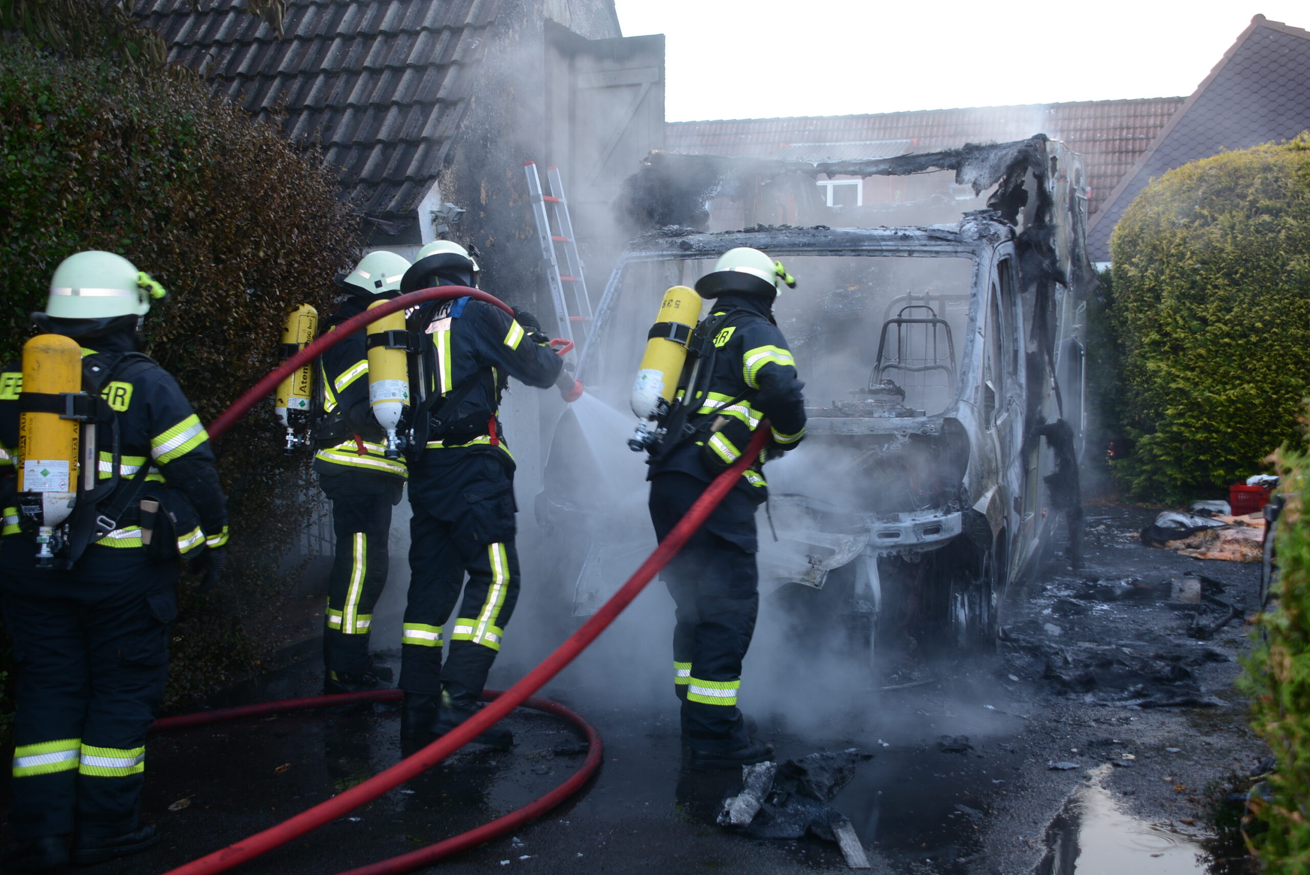 Feuerwehrkräfte löschen letzte Glutnester am Wohnmobil in Barsbüttel.