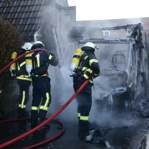 Feuerwehrkräfte löschen letzte Glutnester am Wohnmobil in Barsbüttel.