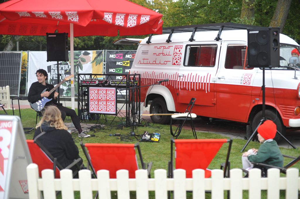 Ein rot-weißes Mopo-Auto, ein DJ-Pult und ein Musiker sind auf dem Heiligengeistfeld zu sehen