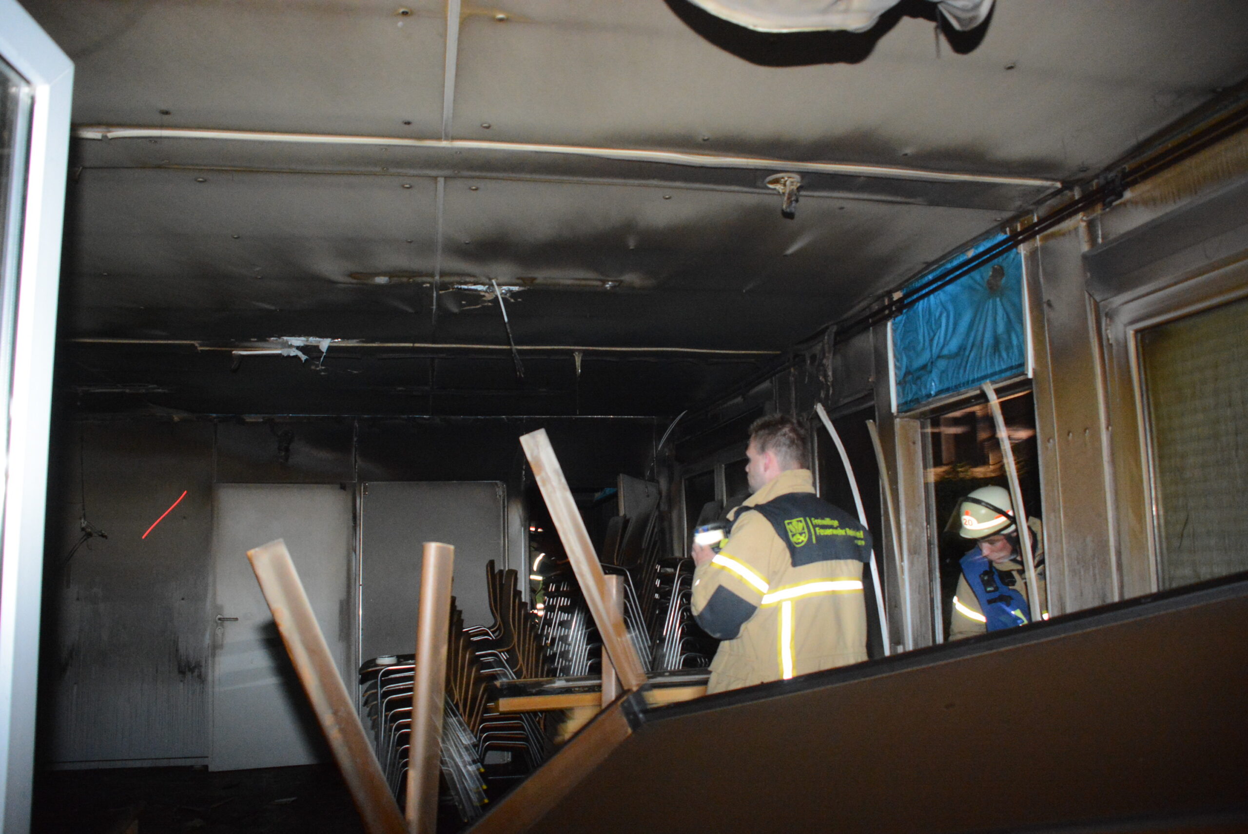 Feuerwehrkräfte in dem stark beschädigten Container.