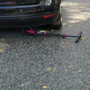 Ein Tretroller liegt unter einem Golf, daneben geht eine Polizistin