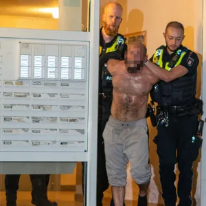 Der Mann wird von Polizisten abgeführt und zum Rettungswagen gebracht.