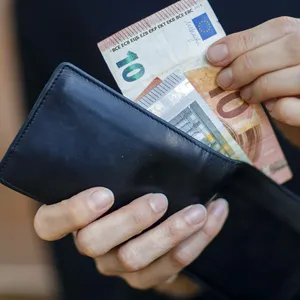 Frau nimmt zwei Geldscheine aus einem Geldbörse.