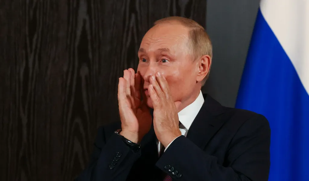 Wladimir Putin hält sich die Hände trichterförmig vor den Mund