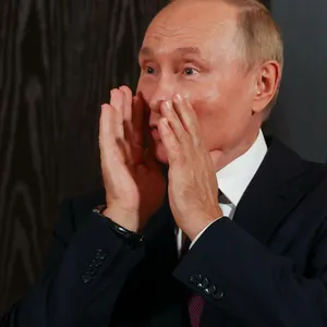 Wladimir Putin hält sich die Hände trichterförmig vor den Mund