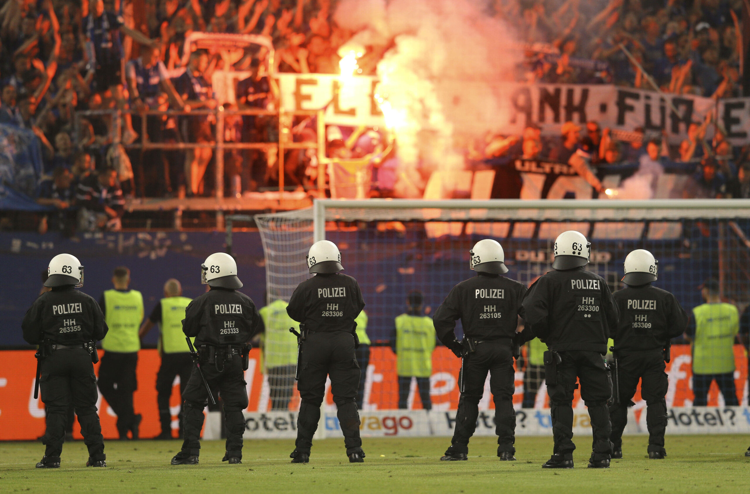 Polizeieinsatz im Volksparkstadion des HSV: Polizisten stehen auf dem Platz, Fans brennen Pyrotechnik ab.