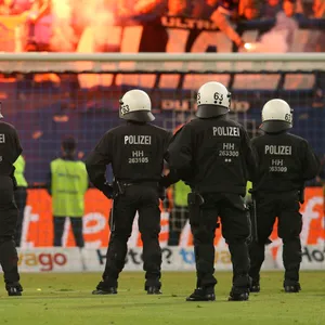 Polizeieinsatz im Volksparkstadion des HSV: Polizisten stehen auf dem Platz, Fans brennen Pyrotechnik ab.