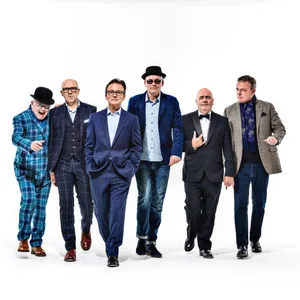 Die Band - alle Männer in Anzügen - vor weißem Hintergrund