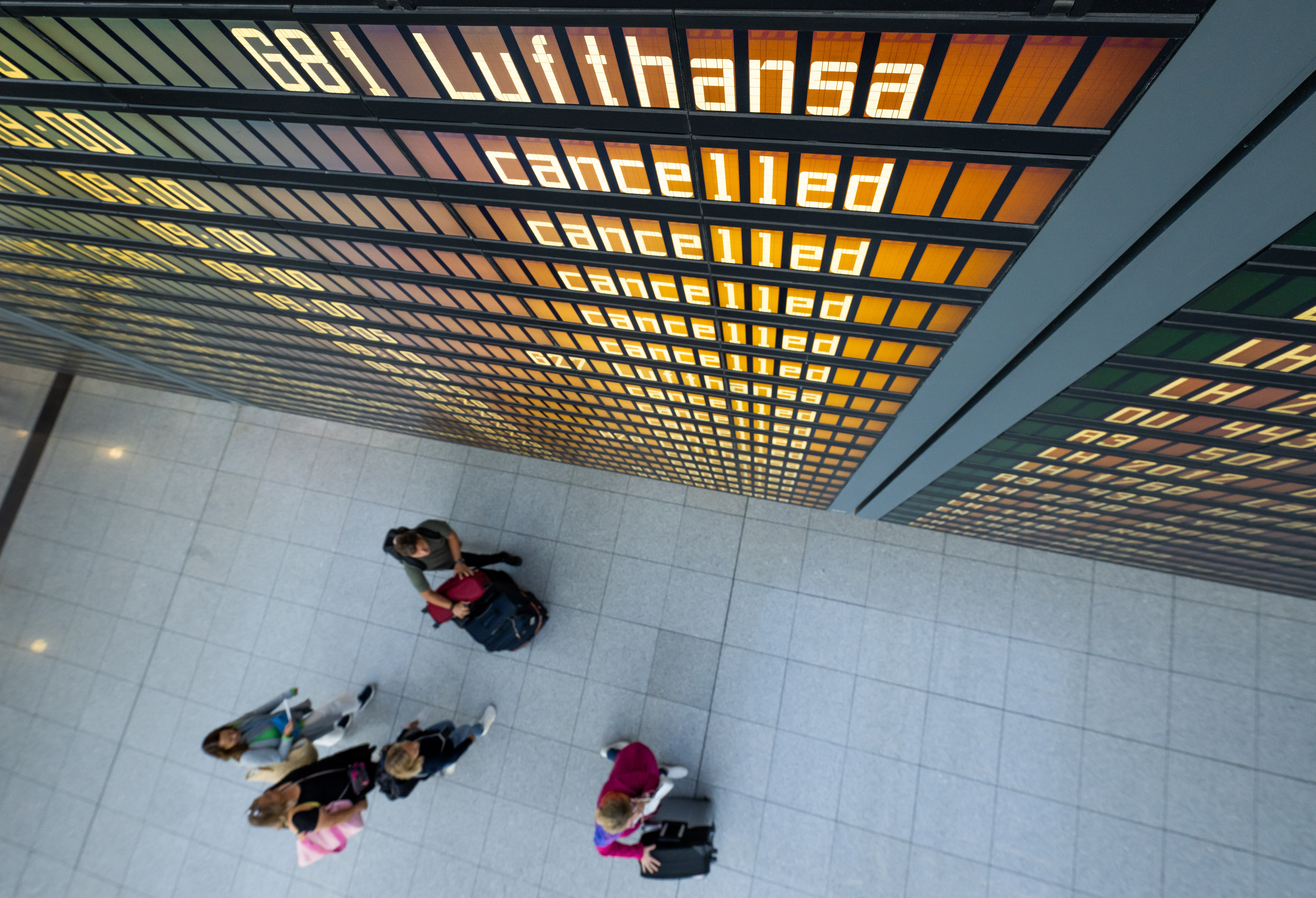 Die Worte "Lufthansa" und "cancelled" sind an einer Anzeigetafel am Flughafen zu lesen.