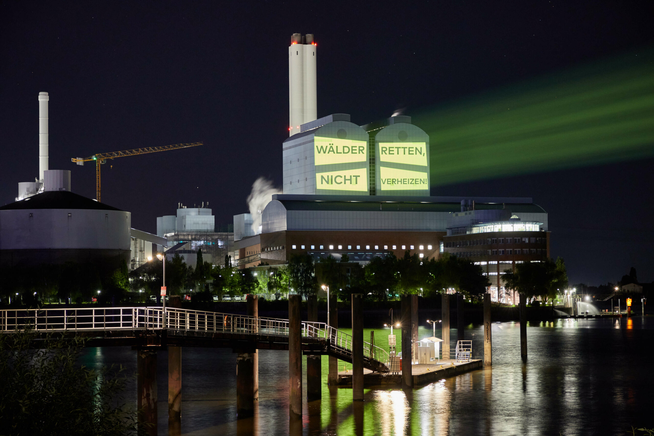 Aktivisten von Robin Wood projizieren den Schriftzug „Wälder retten, nicht verheizen!“ auf das Hamburger Heizkraftwerk Tiefstack.