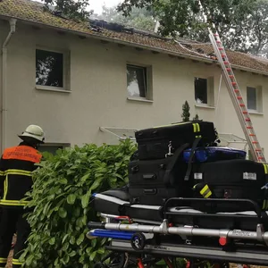 Rettungskräfte stehen vor einem Haus.