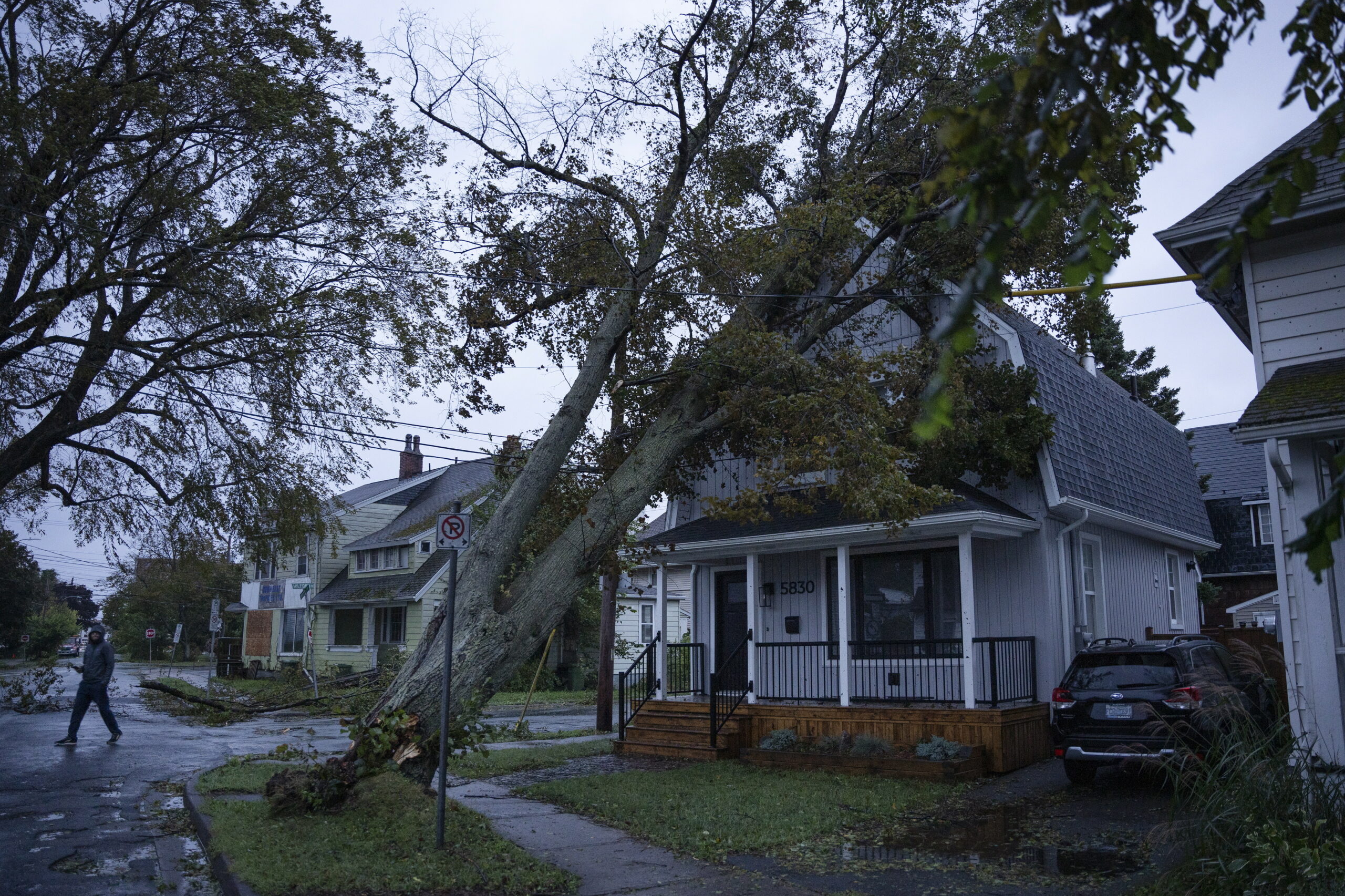 Ein Anwohner begutachtet am frühen Morgen die Schäden an seinem Haus, die durch einen umgestürzten Baum entstanden sind.