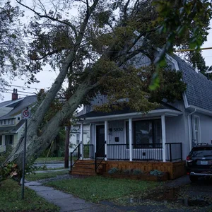 Ein Anwohner begutachtet am frühen Morgen die Schäden an seinem Haus, die durch einen umgestürzten Baum entstanden sind.