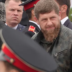 Ein Mann mit langem Bart steht bei einer Militärparade zwischen Soldaten