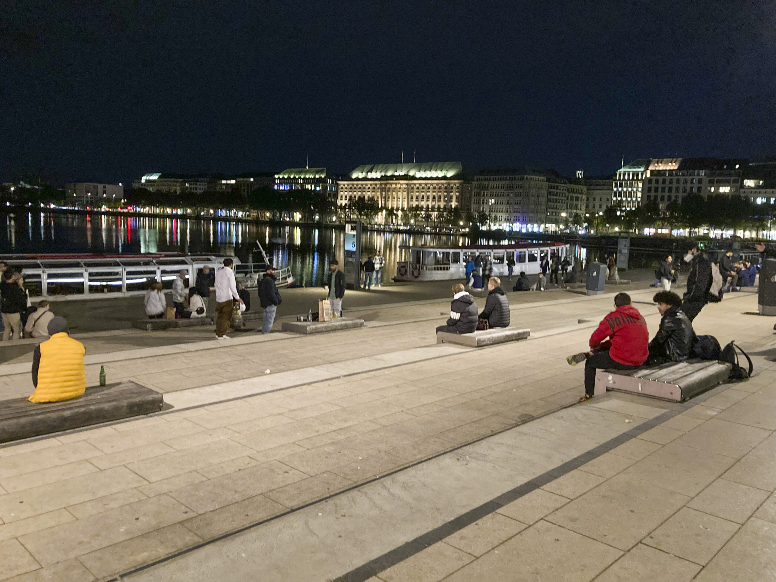 Menschen sitzen am Abend am Jungfernstieg in Hamburg