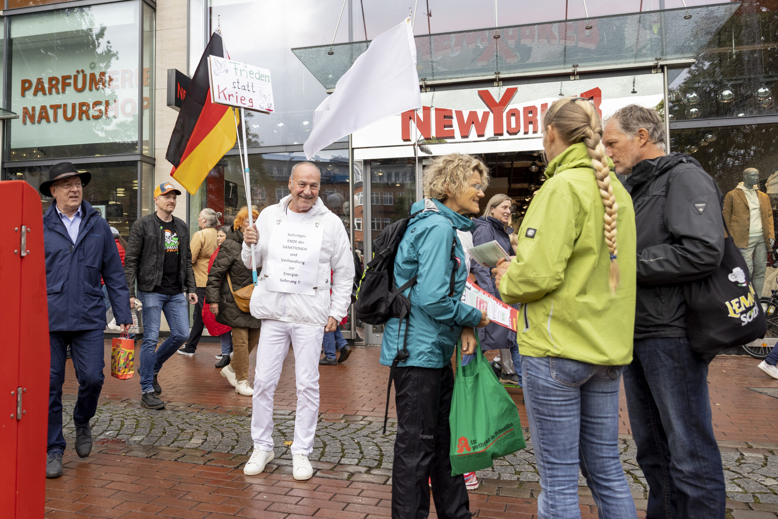 Ein weiß gekleideter Mann hält eine Deutschland-Flagge in die Höhe.