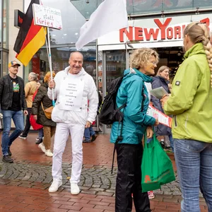 Ein weiß gekleideter Mann hält eine Deutschland-Flagge in die Höhe.
