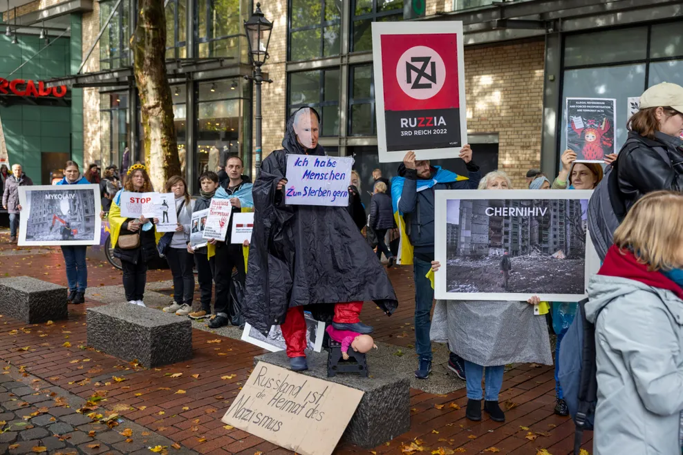 Vor dem „Mercado“-Einkaufszentrum stehen 30-40 ukrainische Gegendemonstranten mit Schildern und Fotos.