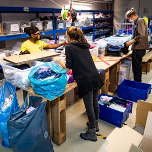 Mitarbeiter:innen von Hanseatic Help sortieren Kleiderspenden. (Archivbild)