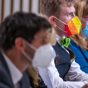 Hannes Damm, Abgeordneter der Grünen-Fraktion, sitzt während der konstituierenden Sitzung des Landtags Mecklenburg-Vorpommern mit einem Mund-Nasen-Schutz in Regenbogenfarben im Plenarsaal.