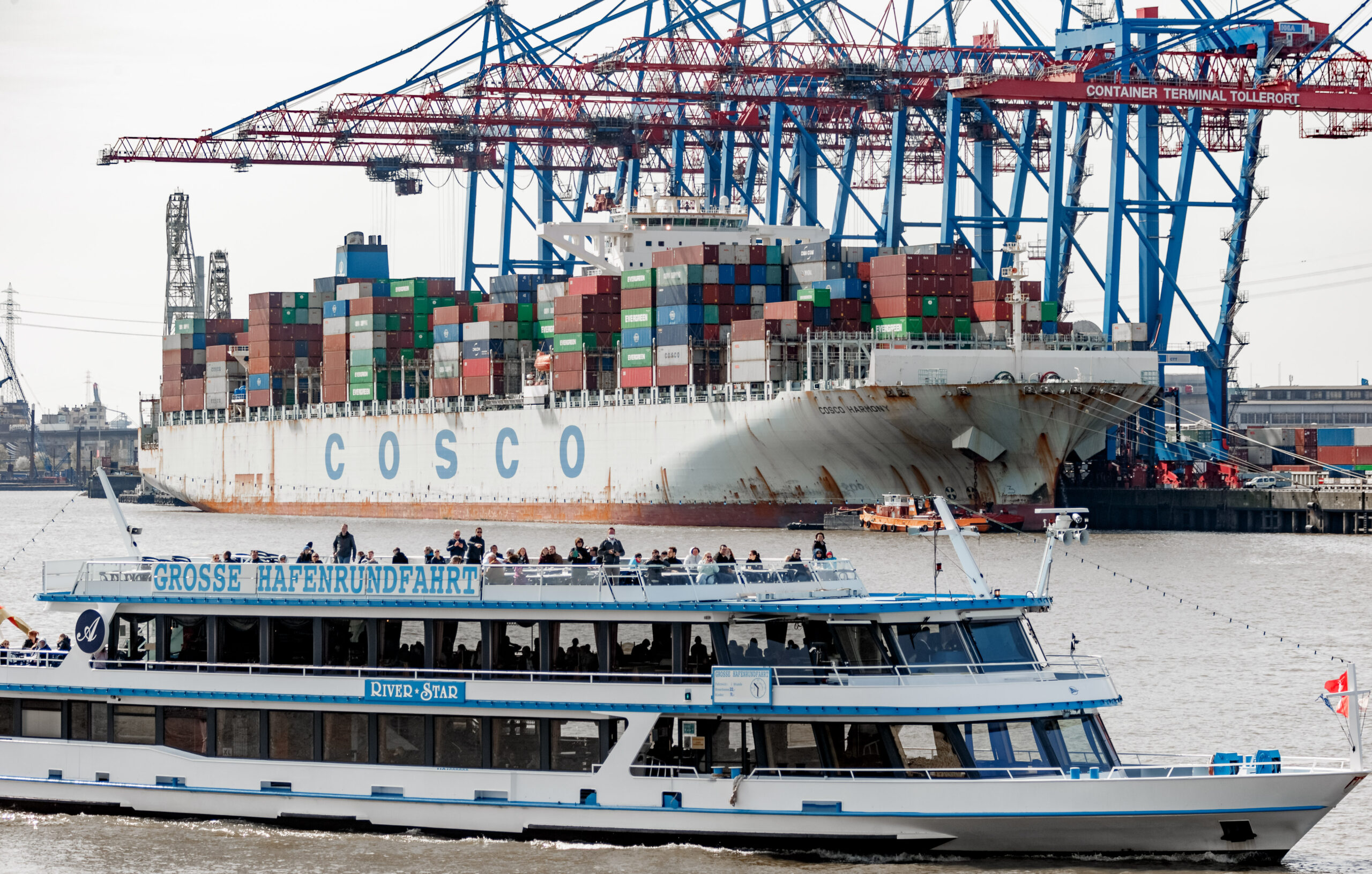 Das Hafenrundfahrtsschiff River Star fährt im Vorhafen am Containerterminal Tollerort vorbei, an dem die COSCO Harmony beladen wird.