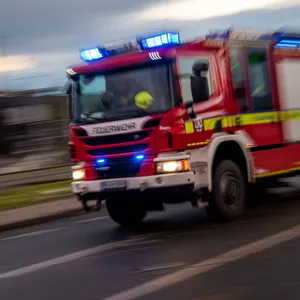 Ein Fahrzeug der Feuerwehr fährt mit Sonderrechten (Blaulicht) über eine Straße.