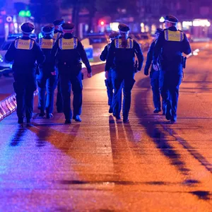 Polizisten laufen nach dem Einsatz zu ihren Streifenwagen (Archivbild).
