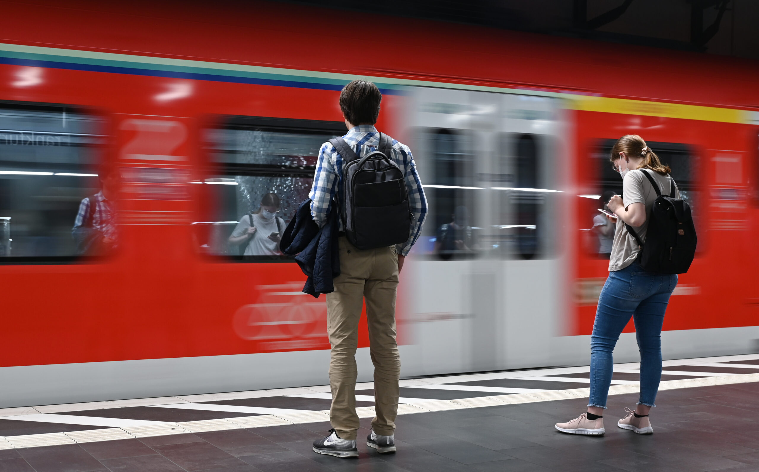 Zugreisende warten am Gleis auf die Einfahrt einer S-Bahn