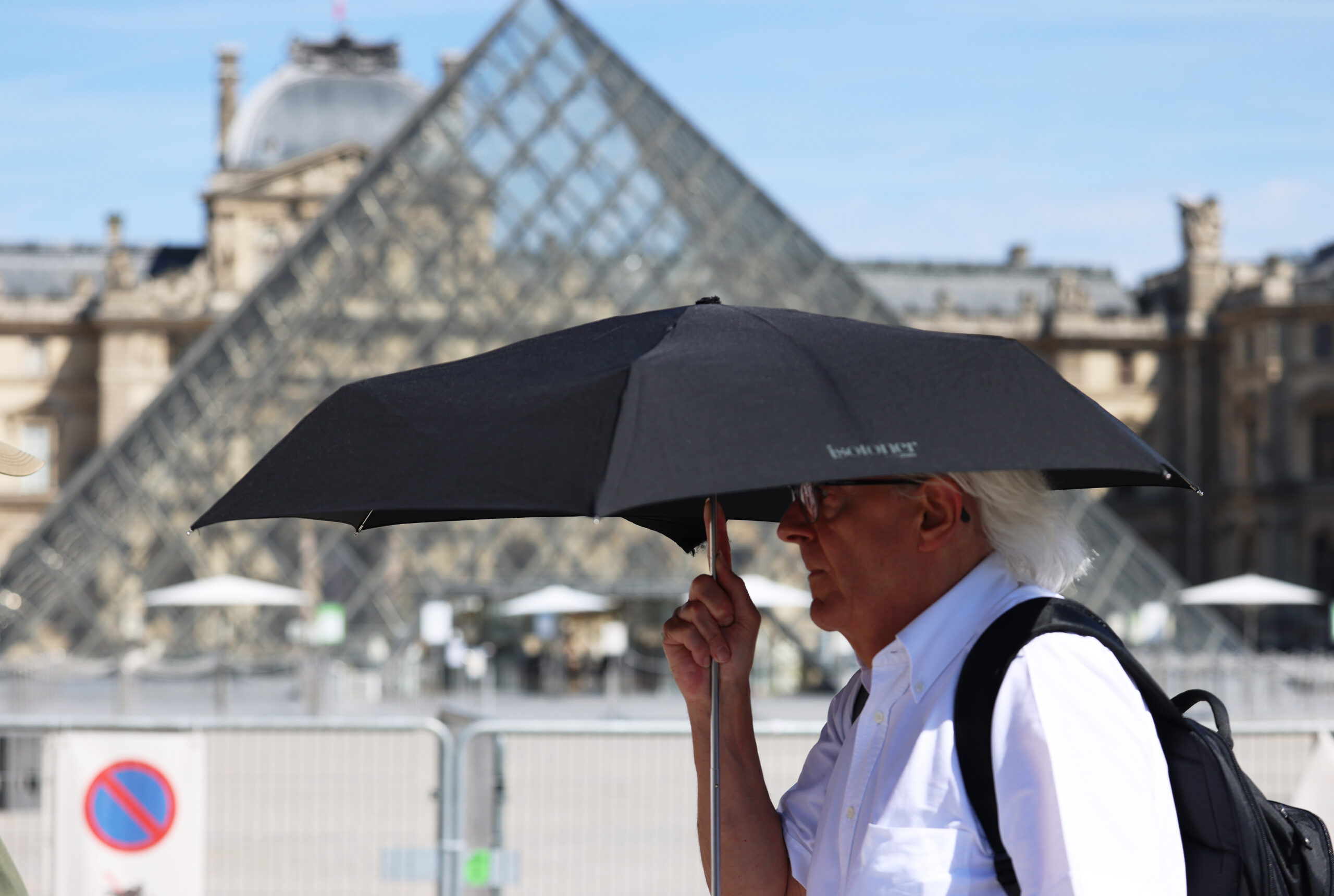Mann schützt sich mit Regenschirm vor der Sonne in Paris