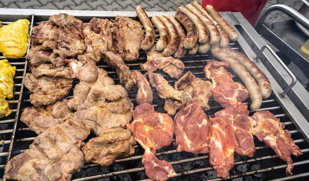Zahlreiche Fleischstücke und Würste liegen auf einem großen Grill. (Symbolbild)