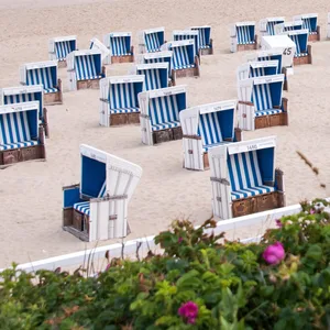 Zwei Spaziergänger sind am Morgen am Strand von Westerland an der Nordsee unterwegs.
