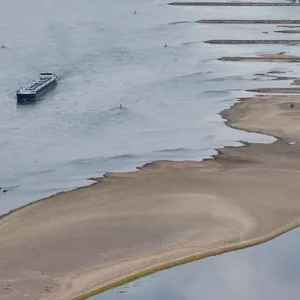 Ein Binnenschiff fährt bei Niedrigwasser an freiliegenden Felsen und Sandbänken auf dem Rhein bei Bacharach.