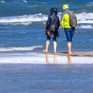 Spaziergänger sind am Ostseestrand von Warnemünde unterwegs.