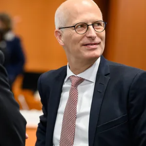 Drei Männer im Anzug stehen in einem Konferenzraum