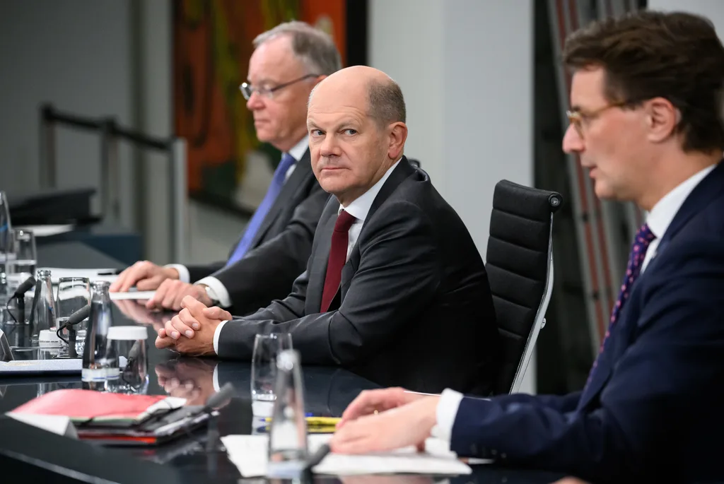 Drei Männer sitzen bei einer Pressekonferenz an einem Tisch