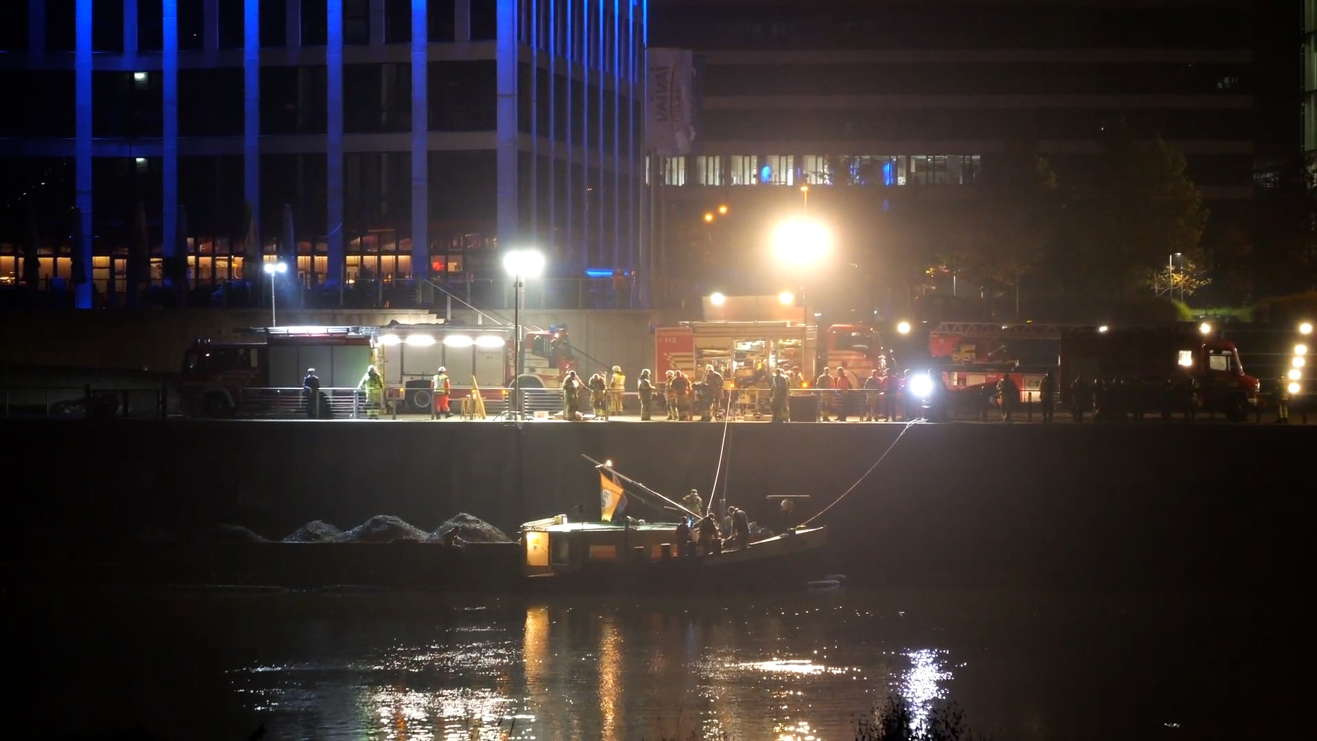 Einsatzkräfte der Feuerwehr arbeiten an einem havarierten Binnenschiff.