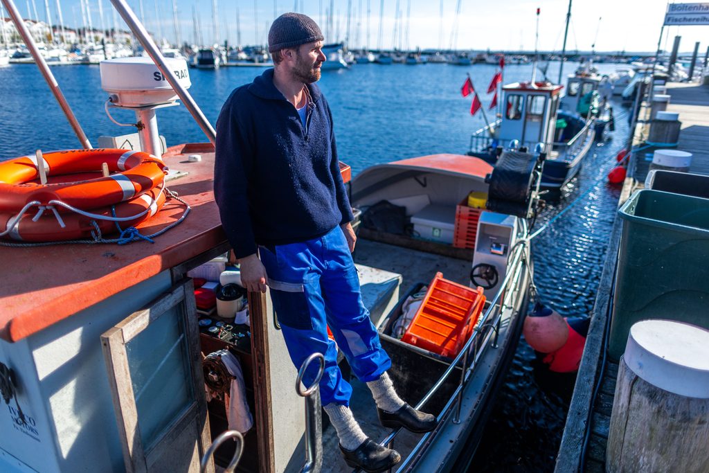 Ostseefischer Hendrik Kern steht auf seinem Fischkutter TAR18 im kleinen Fischerhafen in Tarnewitz an der Ostsee.