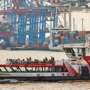 Eine HADAG-Fähre fährt an den Kränen und Containerschiffen im Hamburger Hafen am HHLA-Terminal Tollerort vorbei.