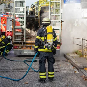Feuerwehrmänner kühlen die heißgelaufenen Lkw-Bremsen mit Wasser.