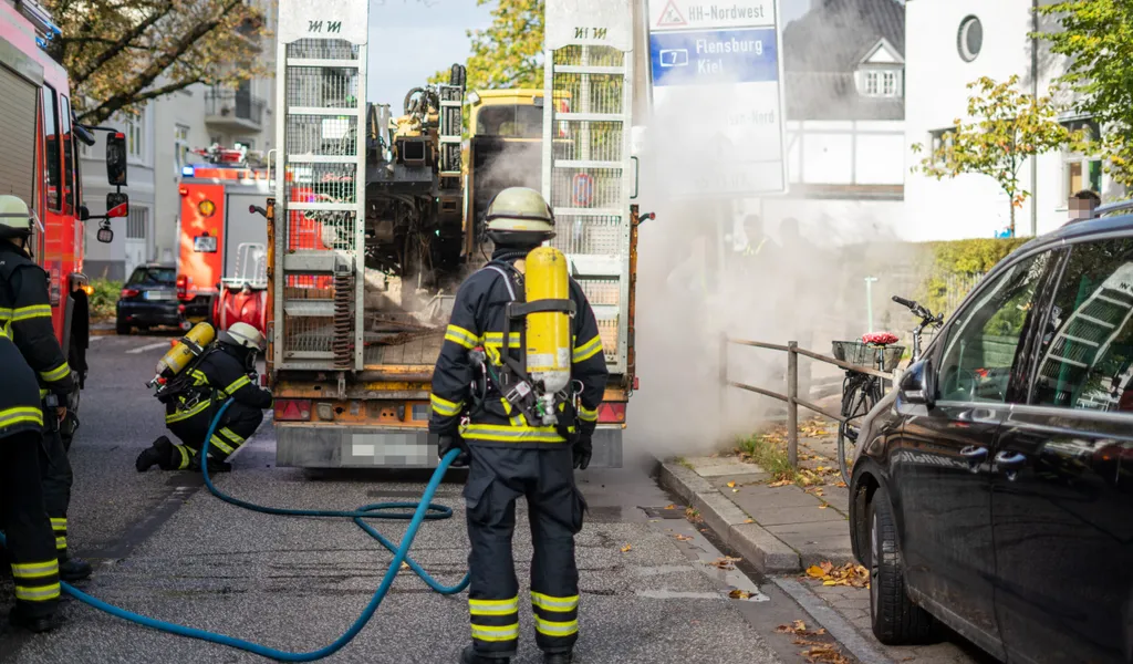 Feuerwehrmänner kühlen die heißgelaufenen Lkw-Bremsen mit Wasser.