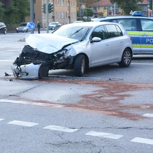 Die Front eines silbernen Golfs ist komplett zerstört, dahinter ein Polizeiauto